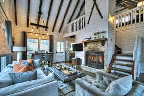 A spacious living room with a fireplace, wooden beams, and a comfortable seating area.