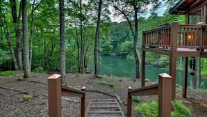 Eine Holztreppe führt zu einer Aussichtsplattform mit Blick auf einen von Bäumen umgebenen See.