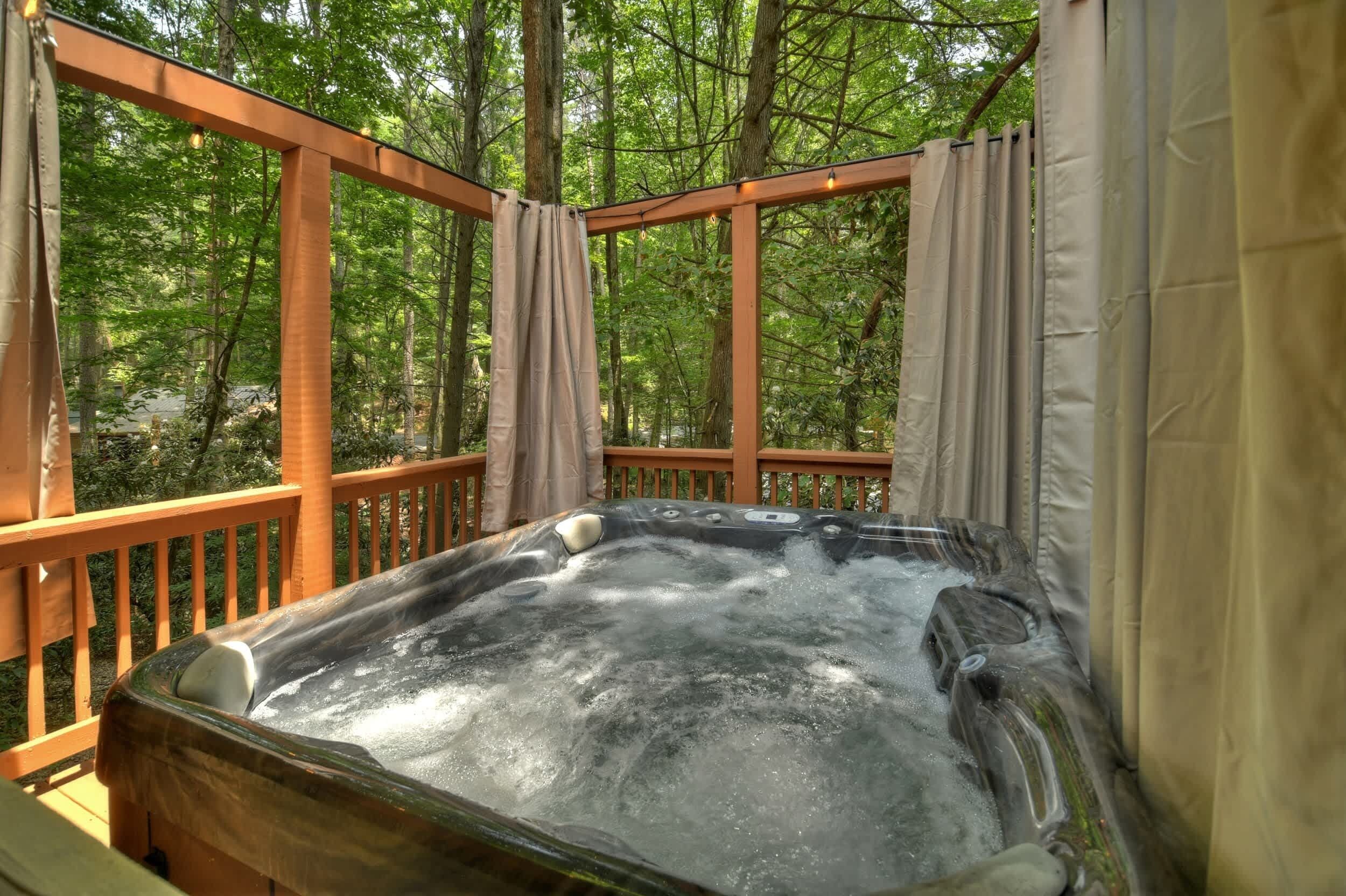 A hot tub on a wooden deck surrounded by trees.