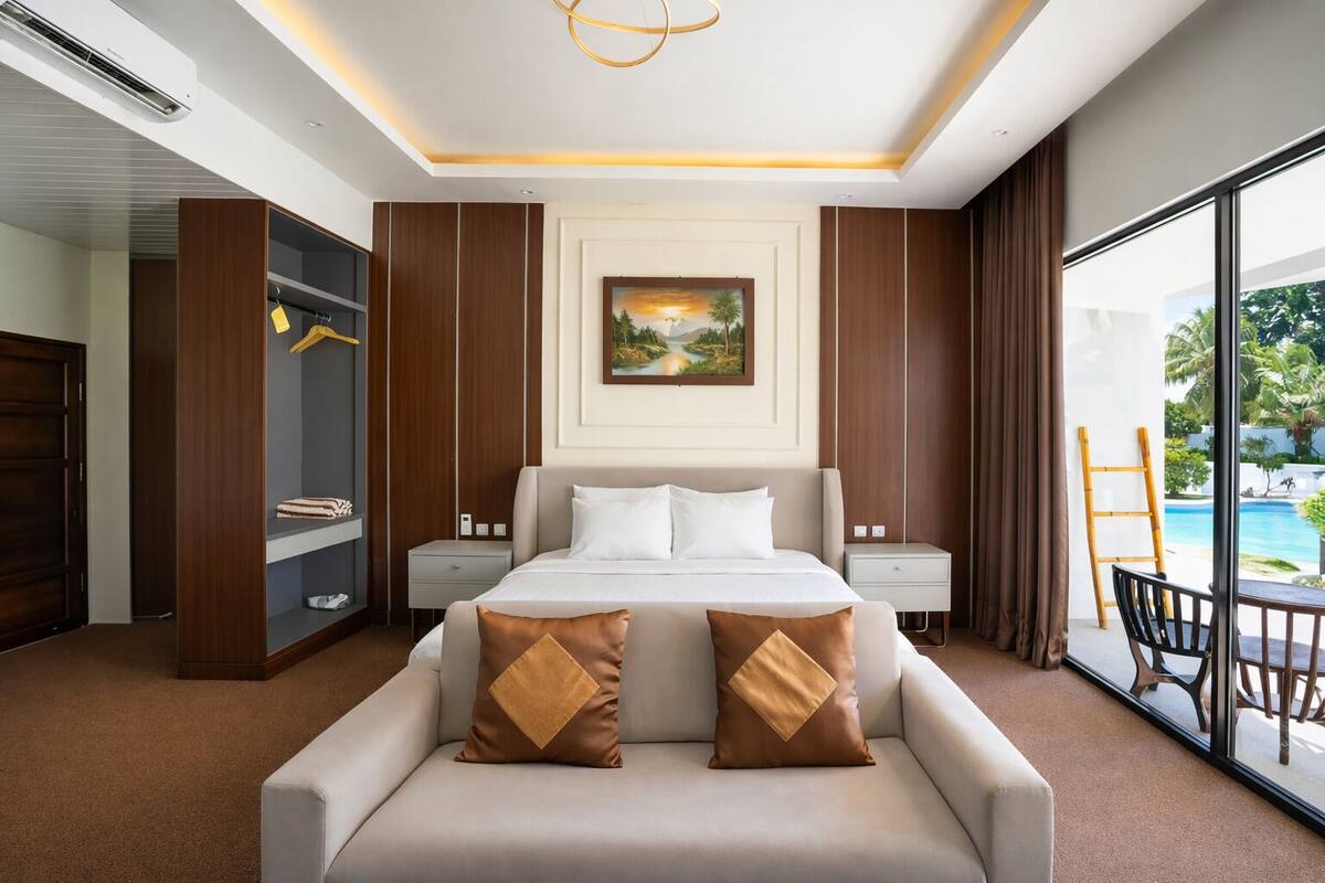 Habitación de hotel moderna con una cama grande, un sofá, un cuadro en la pared y vistas a una piscina.