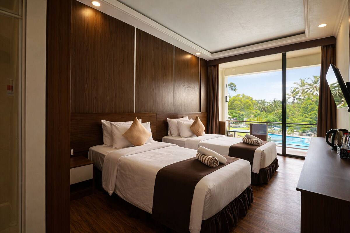 Habitación de hotel con dos camas, un ventanal con vistas a una piscina y palmeras, y un escritorio con cafetera.