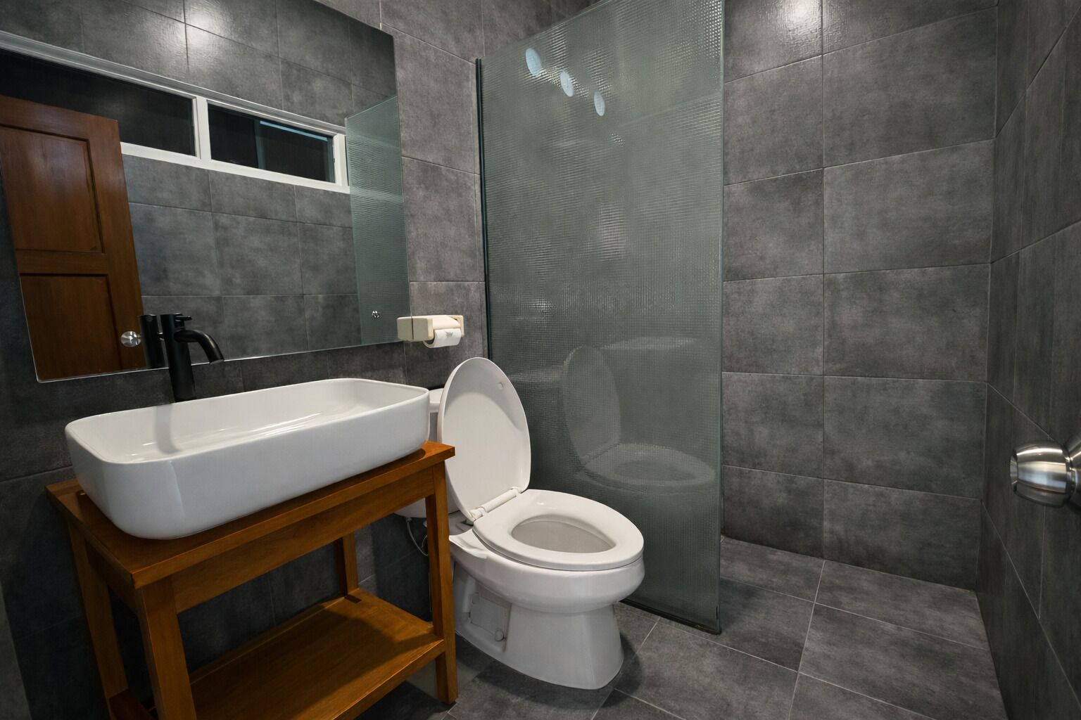 Un baño moderno con un lavamanos grande y rectangular, un inodoro y un box de ducha.