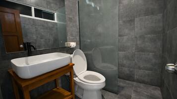 Un baño moderno con un lavamanos grande y rectangular, un inodoro y un box de ducha.
