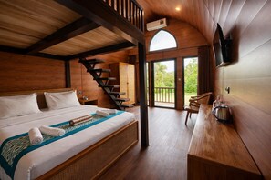 A wooden cabin-style room with a bed, a staircase, a dining area, and a view of the outdoors. - Nirvana Hotel Resort Tetebatu (Tetebatu)