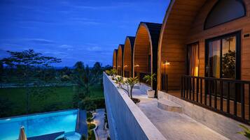 A modern building with a pool, surrounded by greenery and palm trees.
