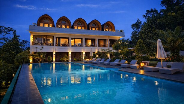 A modern hotel with a large pool, multiple balconies, and lush greenery. - Nirvana Hotel Resort Tetebatu (Tetebatu)