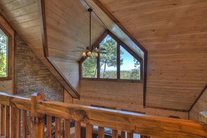 Features a sloped ceiling and stone wall, with a wooden railing.