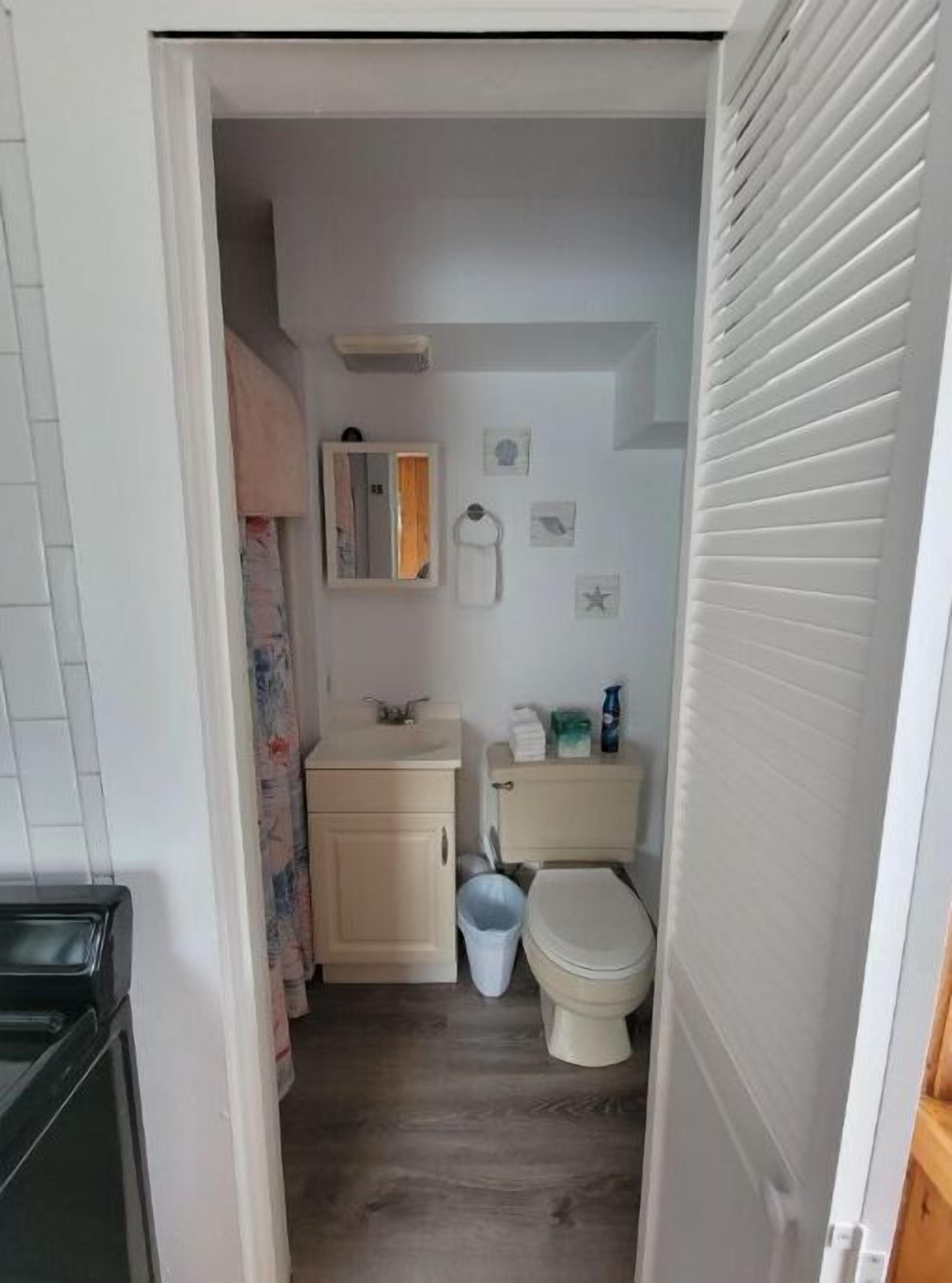 A small, narrow bathroom with a toilet, sink, and cabinet.