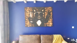 A room with a blue wall, a brown sofa, and a golden throw blanket.