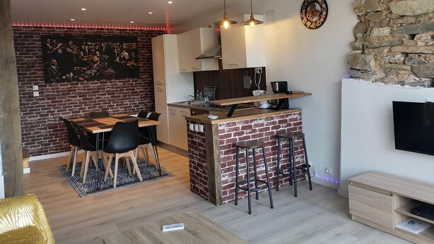 A modern kitchen with a brick island, bar stools, and a dining area with a table and chairs.