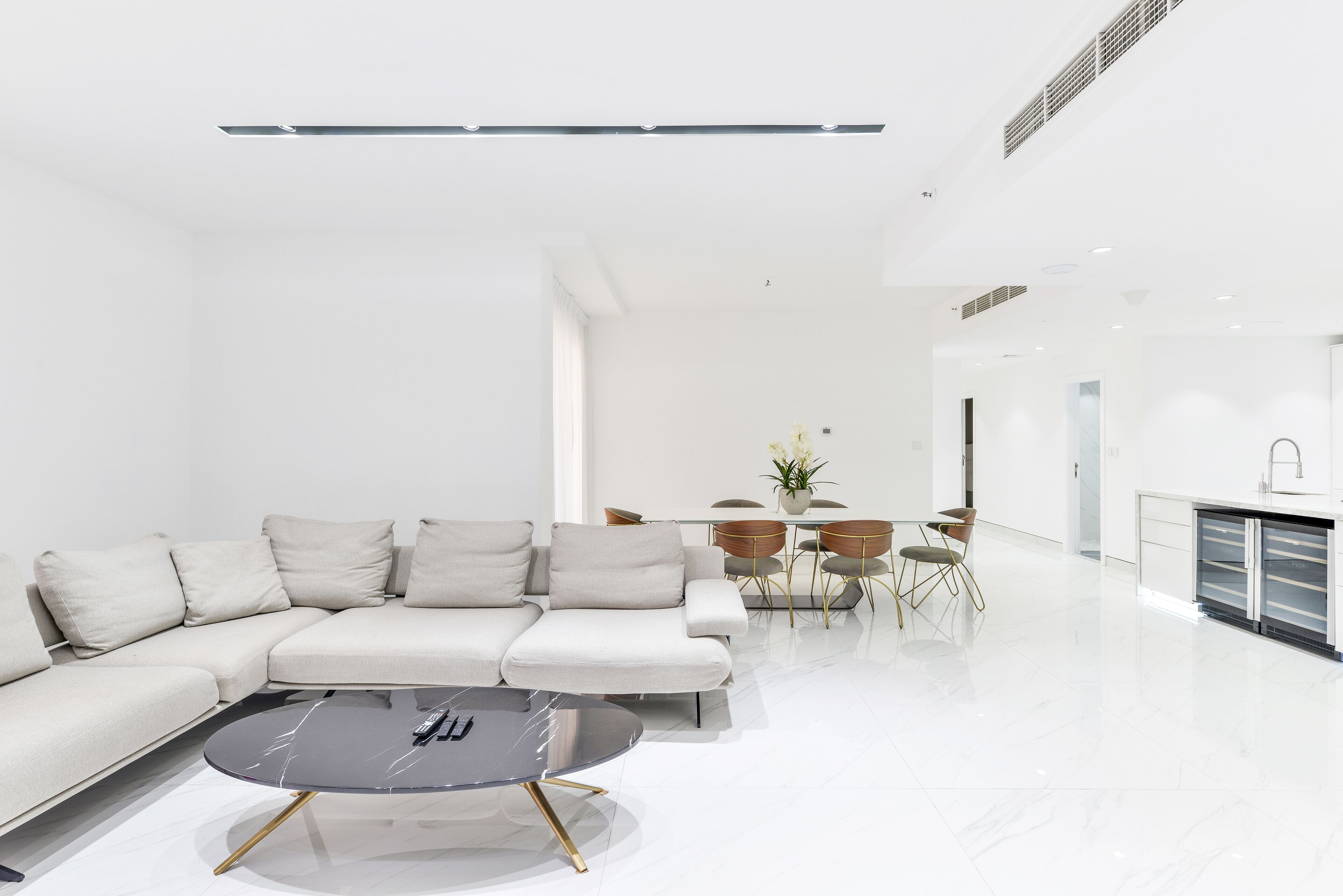 A modern living room with a sectional sofa, a round coffee table, and a dining area with a table and chairs.
