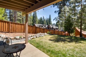A covered patio with a table and chairs, a wooden fence, and a view of houses and trees. - Updated Lake Almanor Retreat w/ Patio & Grill! (Westwood)