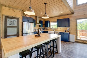 Une cuisine moderne avec un îlot central en bois, des tabourets de bar et des luminaires suspendus.