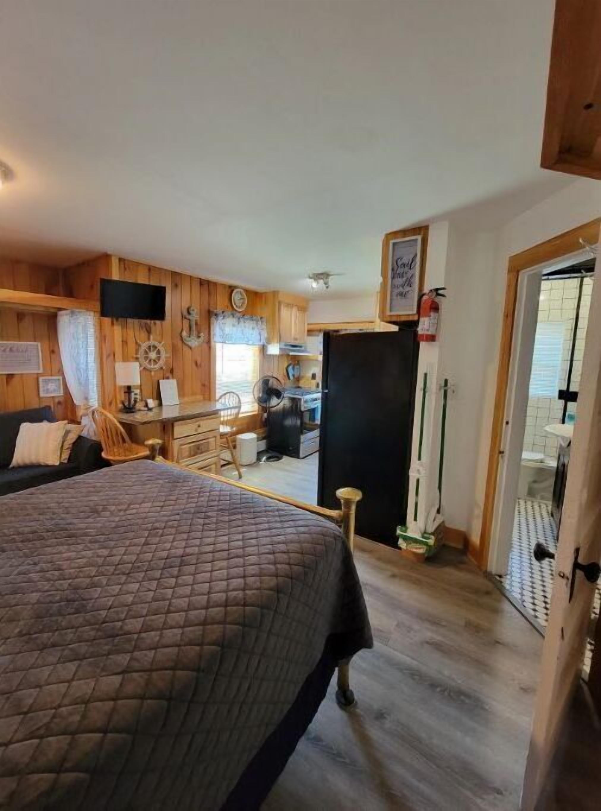 Une pièce confortable avec un lit, un bureau et une petite kitchenette.