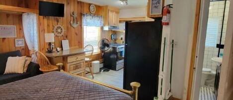 Une pièce confortable avec un lit, un bureau et une petite kitchenette.