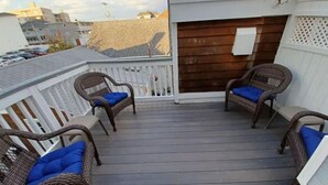 Een overdekt terras buiten met rieten meubels en een blauwe mat.