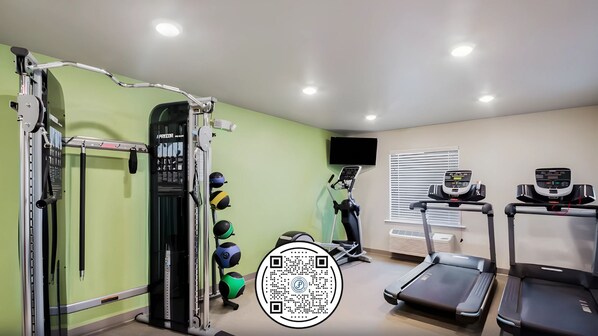 Un gimnasio con equipamiento de ejercicio, cintas de correr y un televisor montado en la pared.