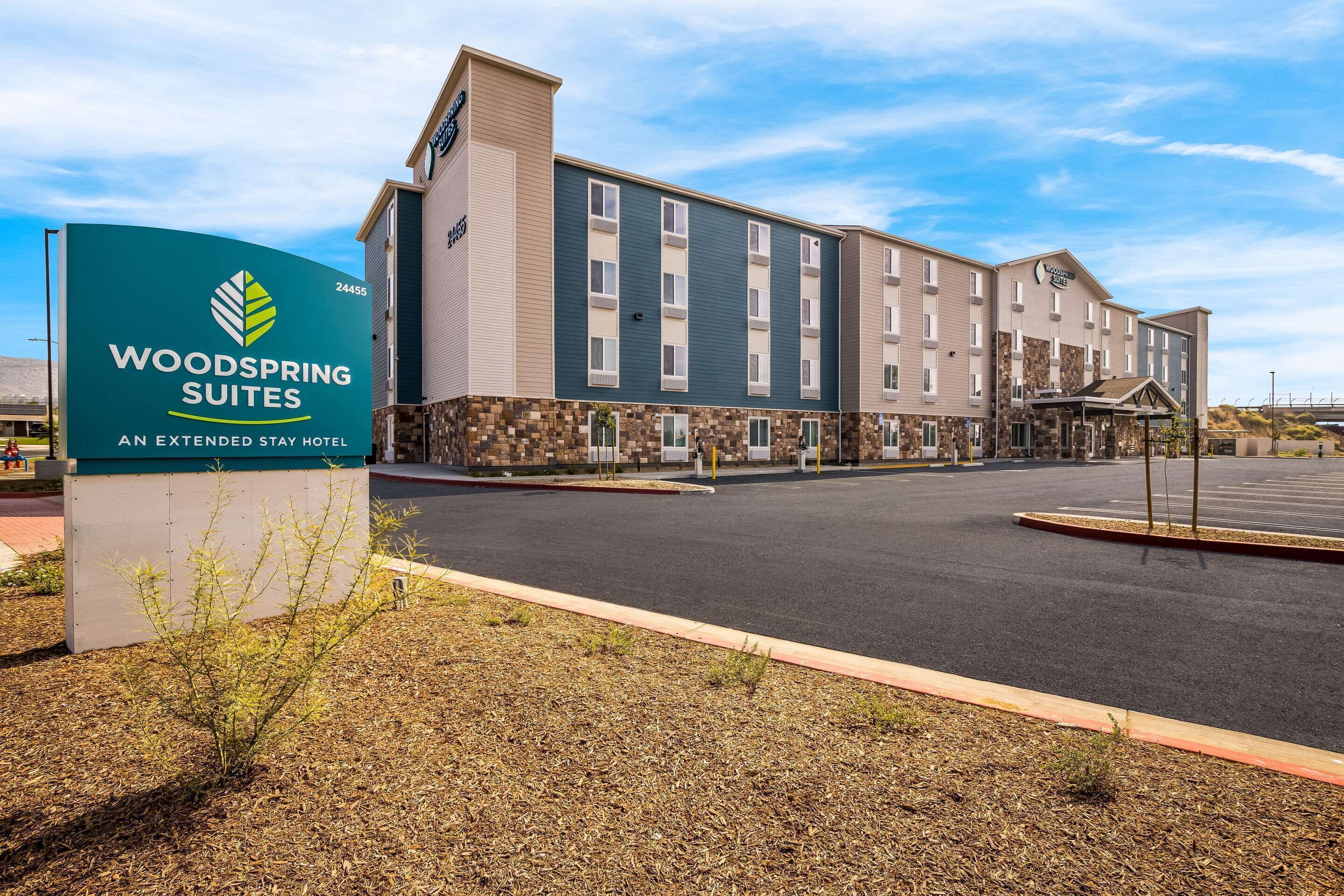 Un hotel con un letrero que dice "Woodspring Suites" y una fachada de edificio moderna.