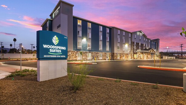 Un hotel con una segnaletica che riporta "Woodspring Suites" e una facciata moderna dell'edificio.
