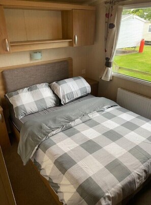 Cozy sleeping area with a bed, storage cabinet, and window offering a view of the outdoors.