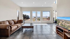 A spacious living room with a leather sofa, a coffee table, and a flat-screen TV.