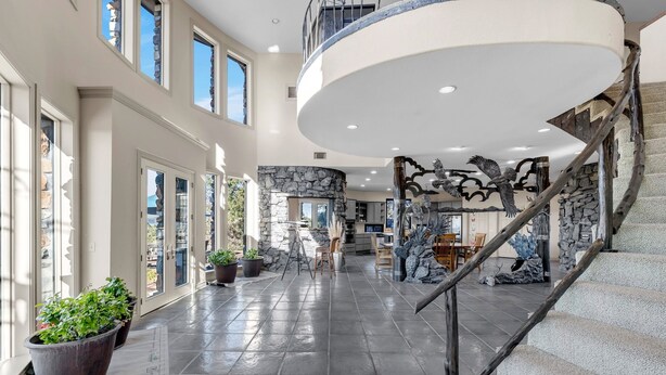 A spacious interior with a grand staircase, large windows, and a stone wall.