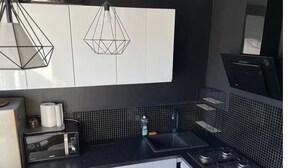 A modern kitchen with black countertops, white cabinets, a gas stove, a microwave, and a hanging light fixture. - Silesia City Center Shopping Mall – 2,6 km (Katowice)