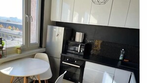A compact kitchen with white cabinets, a black countertop, and a dining area with a white table and chairs. - Silesia City Center Shopping Mall – 2,6 km (Katowice)