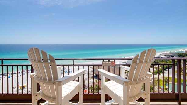 Two white Adirondack chairs facing a beach with a clear view of the ocean and a sign on the balcony railing. - Westwinds 4786 (Miramar Beach)