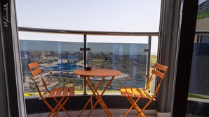 A balcony with a table and two chairs, overlooking a resort area with buildings and a pool. - Lovely 13-bed Complex on Cape Point Beach, Bakau - Bojang River Lodge (Bakau)