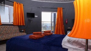 A hotel room with a bed, a sofa, a TV, and a window with curtains. - Lovely 13-bed Complex on Cape Point Beach, Bakau - Bojang River Lodge (Bakau)
