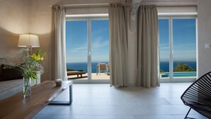 Een moderne kamer met een grote schuifglazen deur die uitkomt op een balkon met uitzicht op zee.
