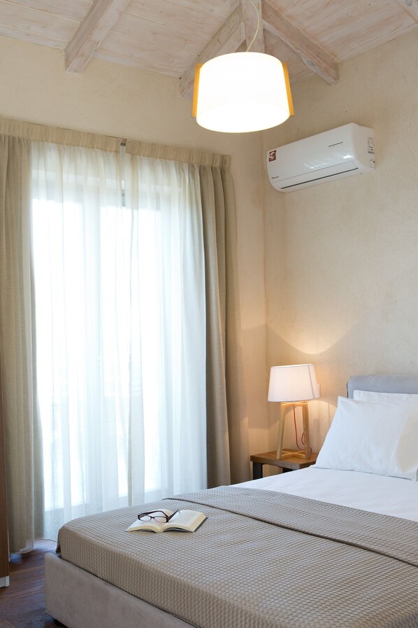 Habitació d'hotel amb un llit, aire condicionat, una làmpada i una finestra amb cortines.
