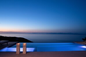 Una piscina infinitat amb vistes al mar a la posta de sol.
