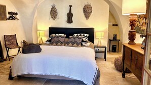 Un dormitorio con una cama grande, dos mesitas de noche, una silla y decoración mural.
