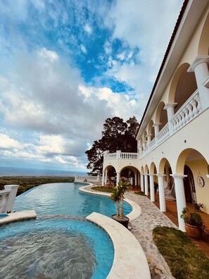 A resort with a pool, outdoor seating, and a view of the ocean.