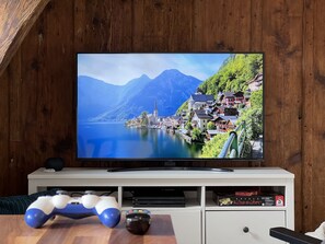 A TV on a wooden wall displaying a scenic village by a lake.