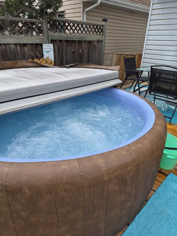 A hot tub with a wooden deck, a wooden fence, and a patio area with chairs. - Beach Retreat with Hot Tub | 1 Block to Beach | Free Parking (Sylvan Lake)