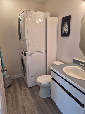 A compact bathroom with a washing machine, toilet, and sink. - Beach Retreat with Hot Tub | 1 Block to Beach | Free Parking (Sylvan Lake)