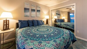 A bedroom with a large bed, two bedside lamps, a ceiling fan, and a large mirror. - Waterfront Condo: Stunning Sunsets, Fishing, Pool, Private Patio, Near Beach  (Corpus Christi)