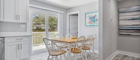 A modern kitchen with white cabinets, a wooden dining table, and four chairs.