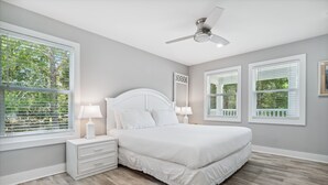 A bedroom with a large bed, white nightstands, and two wall-mounted lamps. - 30A Beach House - Vitamin Sea by PHG (Santa Rosa Beach)