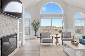 Ein geräumiges Wohnzimmer mit Kamin, großen Fenstern und Blick auf die Landschaft.
