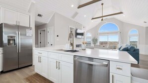 A modern kitchen with white cabinetry, stainless steel appliances, and a large island. - Relaxing Oceanfront Retreat | Pool, Hot Tub & Beach - Sleeps up to 14! (Rodanthe)