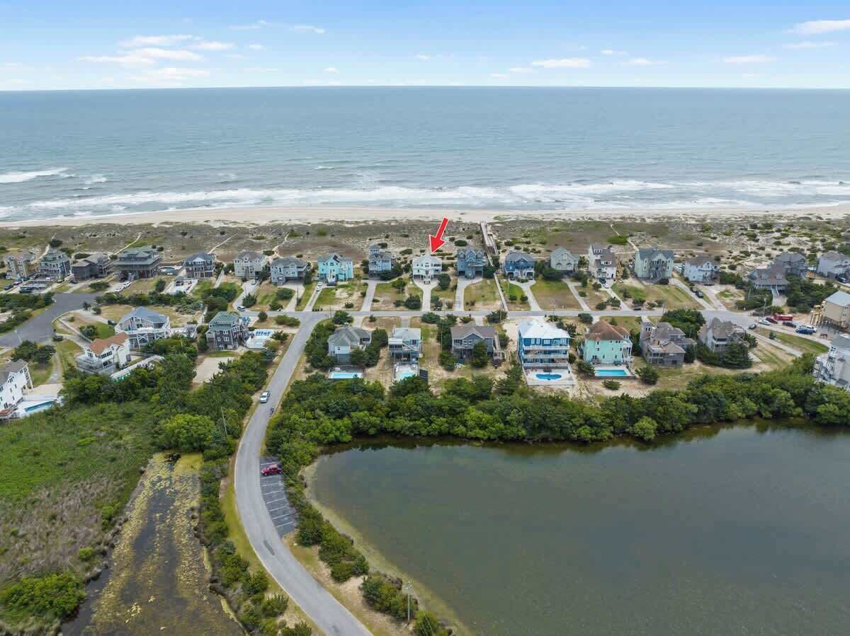 Vue aérienne d’une zone résidentielle côtière, avec des maisons, une plage et une étendue d’eau.