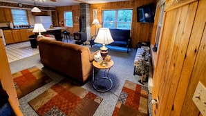 Un interior de cabaña acogedor, con un sofá, dos lámparas, un televisor y una chimenea.