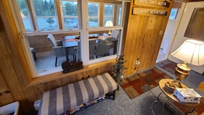 Interior acogedor de una cabaña con comedor, un banco y un letrero que dice 'HAMILTON'S NORTH COUNTRY ADVENTURES'.