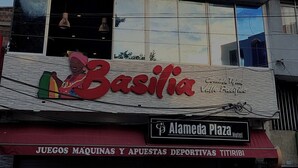 Un immeuble à plusieurs étages, avec une enseigne « Bacilia » au rez-de-chaussée, un balcon au deuxième étage et une enseigne « Alameda Plaza Hotel » au troisième étage.