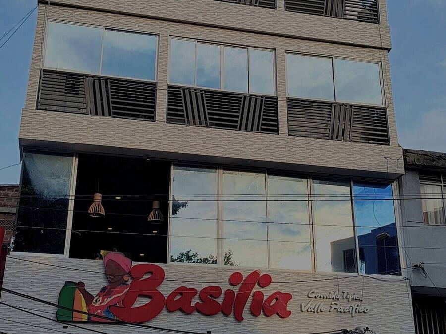 A multi-story building with a sign for 'Bacilia' on the ground floor, a balcony on the second floor, and a sign for 'Alameda Plaza Hotel' on the third floor.