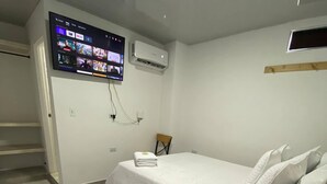 Une chambre d’hôtel avec un lit, un téléviseur fixé au mur, une chaise et une table en bois avec une télécommande.